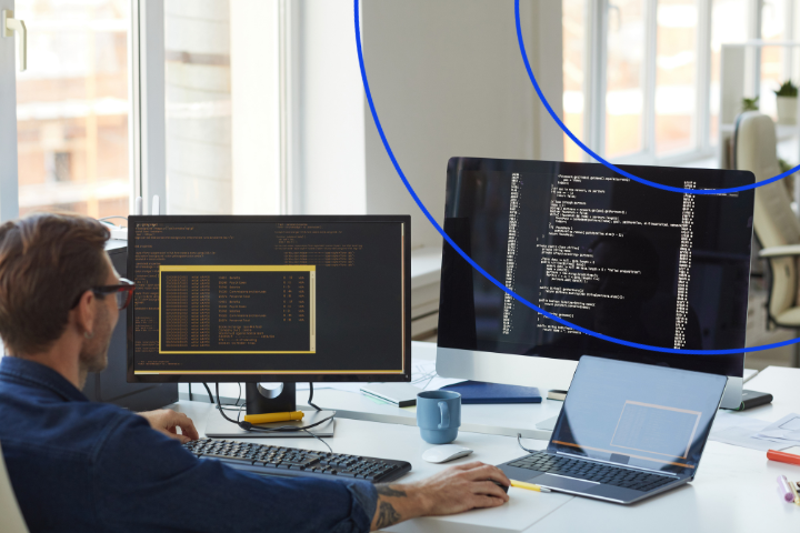 Programátor pracujúci na počítači s dvoma monitormi zobrazujúcimi kód