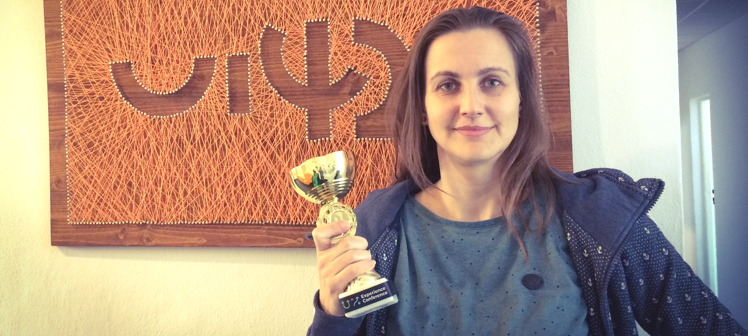 Žena držiaca trofej pred umeleckým pozadím na konferencii
