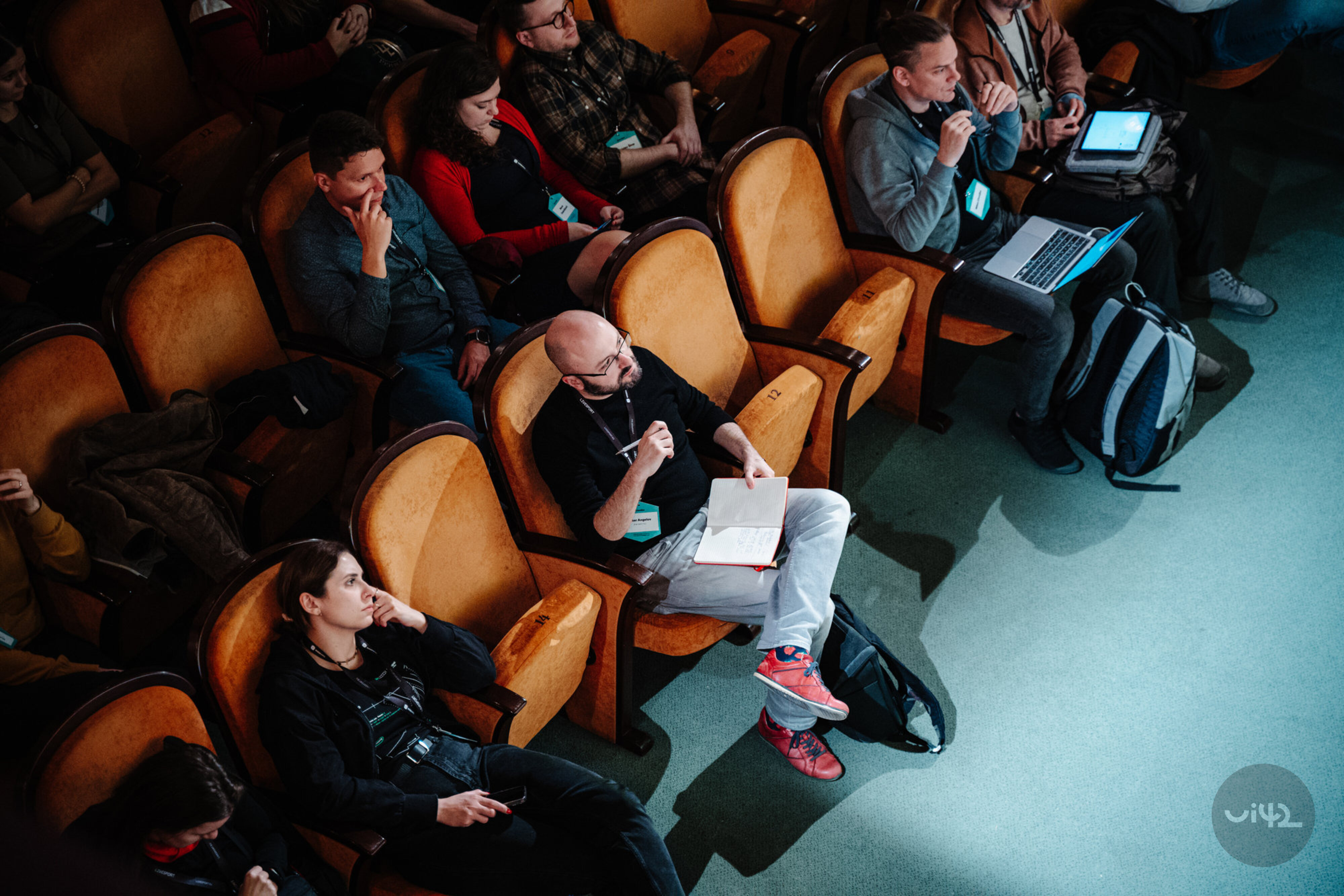 Ľudia sedia v hľadisku počas konferencie Webexpo 2023, niektorí si robia poznámky, iní používajú notebooky.