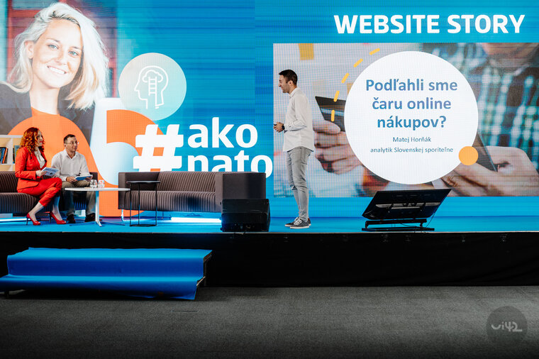 Účastníci konferencie Website Story na pódiu počas prezentácie o online nakupovaní. Na obrazovke za nimi je text: Podľahli sme čaru online nákupov? Matej Horňák, analytik Slovenskej sporiteľne.