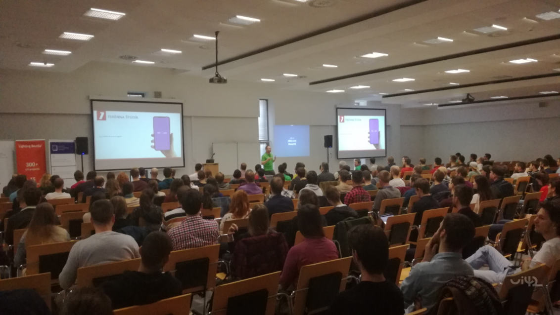 Fotografia z konferencie WUD 2018 s účastníkmi v prednáškovej miestnosti, prezentáciou na plátne a prednášajúcim.