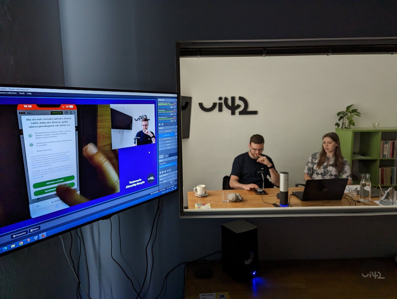 Testovanie použiteľnosti v kancelárii s dvoma osobami pri stole a obrazovkou zobrazujúcou mobilný telefón.