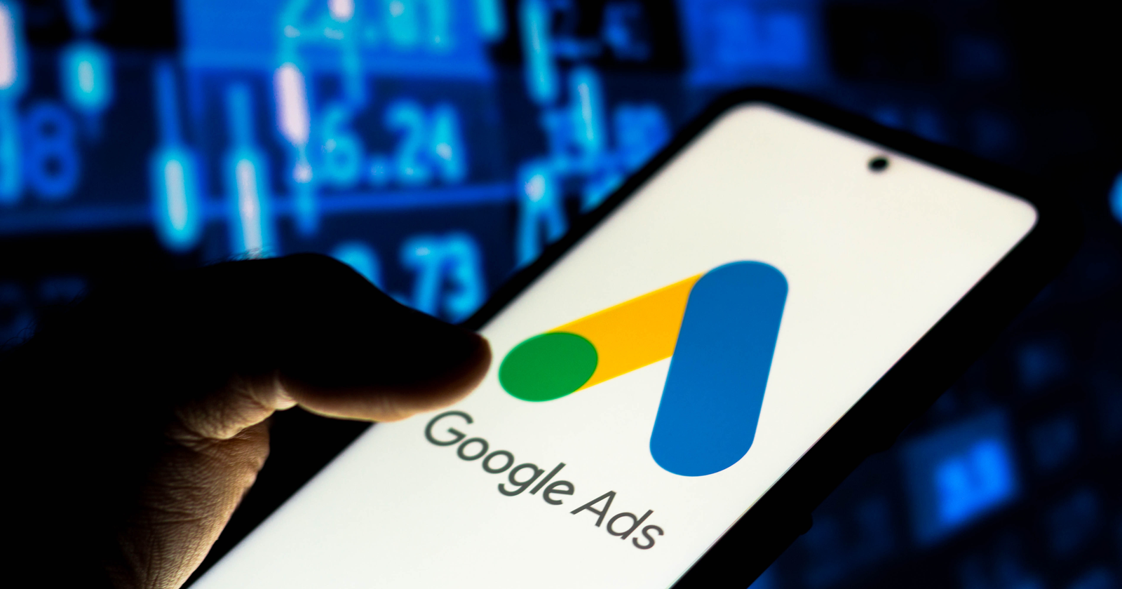 Logo Google Ads na mobilnom zariadení s rozmazaným pozadím obrazovky s grafmi.