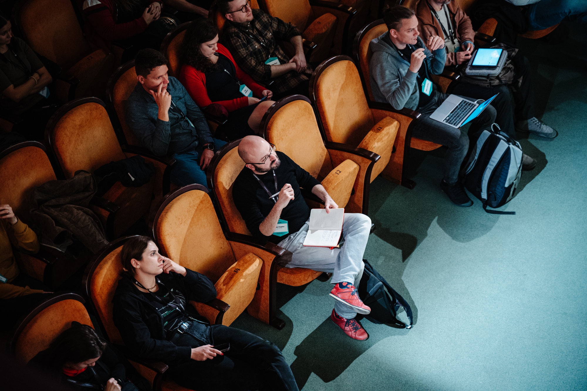 Ľudia sedia v hľadisku počas konferencie Webexpo 2023, niektorí si robia poznámky, iní používajú notebooky.